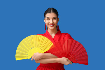 Wall Mural - Beautiful young happy woman with fans on blue background. Chinese New Year celebration