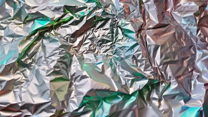 Poster - The crumpled foil lies flat with a myriad of colors reflecting under natural light, showcasing intricate textures and shimmering surfaces.