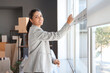 © Pixel-Shot - Beautiful businesswoman lowering window blinds in office on moving day