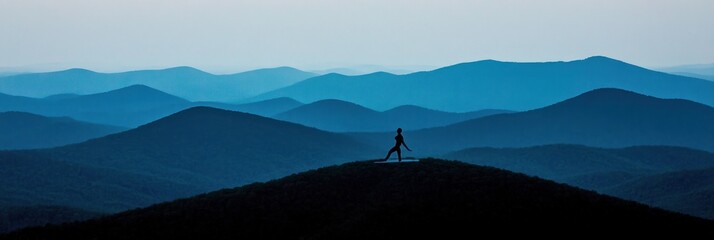 Sticker - Silhouette of a person standing on a mountain peak with a view of distant blue mountains.