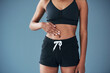 © peopleimages.com - Body, gut health or hands of woman on stomach and diet to lose weight for fitness or training. Blue background, sportswear or girl athlete touching abdomen in studio for exercise results or digestion