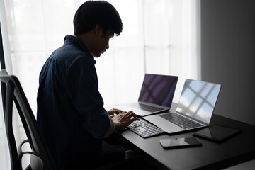 Asian man software engineer Working on Computer at office desk for writing program code IT Software Engineer finding errors tech support devops creating digital