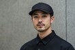 © pham - 若い男性が黒のシャツとキャップを着て、都会の背景でポーズをとる様子を捉えた一瞬