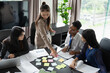 © Wanda - Group of Asian people using sticky notes on meeting table, brainstorming idea in modern office