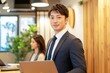 © pham - オフィスで働く若いビジネスマンと女性の同僚が協力し合いながら仕事をしている様子