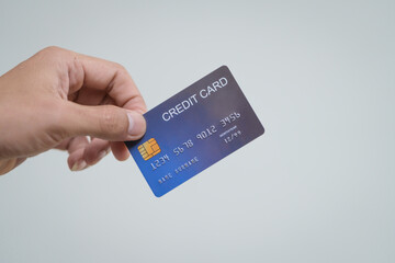 Wall Mural - A close-up of a man’s hand holding a bank credit card against a white background, emphasizing secure online payment services and financial convenience for shopping and banking transactions