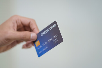 Wall Mural - A close-up of a man’s hand holding a bank credit card against a white background, emphasizing secure online payment services and financial convenience for shopping and banking transactions