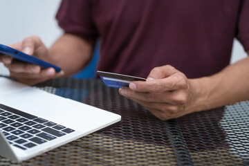 Close-up of a man's hand holding a bank credit card, highlighting online services for lending and access to credit,demonstrating financial convenience and flexibility for secure digital transactions