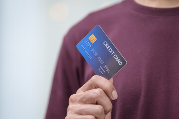 Wall Mural - Close-up of a man's hand holding a bank credit card, highlighting online services for lending and access to credit,demonstrating financial convenience and flexibility for secure digital transactions