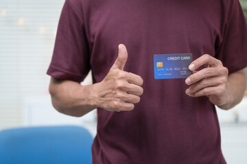 Wall Mural - Close-up of a man's hand holding a bank credit card, highlighting online services for lending and access to credit,demonstrating financial convenience and flexibility for secure digital transactions