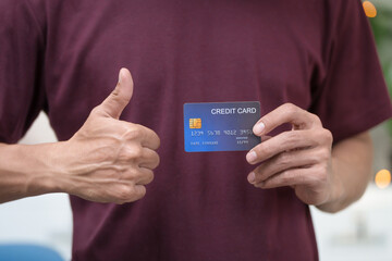 Wall Mural - Close-up of a man's hand holding a bank credit card, highlighting online services for lending and access to credit,demonstrating financial convenience and flexibility for secure digital transactions