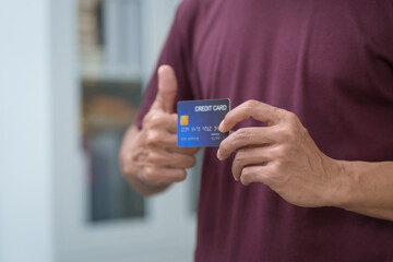 Wall Mural - Close-up of a man's hand holding a bank credit card, highlighting online services for lending and access to credit,demonstrating financial convenience and flexibility for secure digital transactions