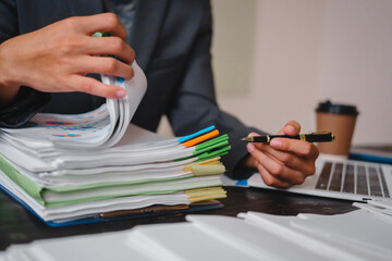 Wall Mural - A businessman works late at his desk, focused on his laptop while talking online. He checks important financial documents, demonstrating dedication and diligence as he manages his overtime tasks