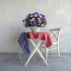 A white table with a red and white polka dot tablecloth and a white chair in front of a grey wall A potted plant with pink and purple flowers sits on the table