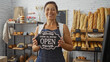 © Krakenimages.com - Woman holding open sign in bakery with bread display in background, smiling, middle-aged, brunette, wearing apron, indoors, shop interior, female, beautiful, mature