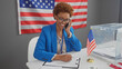 © Krakenimages.com - A smiling african american woman in a blue blazer taking notes in a room with an american flag