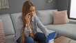 © Krakenimages.com - Woman talking on a phone while using a tablet in a cozy living room with cushions and soft lighting