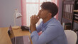 © Krakenimages.com - A handsome young hispanic man sits thoughtfully at his desk in an office, with a laptop, lamp, folders, and phone in an indoor workplace setting.