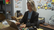 © Krakenimages.com - A focused blonde woman detective working on a laptop in a cluttered police department office, exemplifying a professional law enforcement scene.