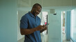 © Krakenimages.com - Young man using smartphone in office interior, smiling and texting, wearing casual blue polo shirt