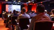 © Ubix - A focused audience attending a conference, with bright lights and a presentation screen visible in the background.