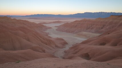 Poster - A view from a high cliff overlooking a desert valley at sunset.