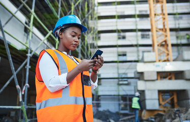 Wall Mural - Black woman, architect or civil engineer with phone at site for construction building or maintenance. Young African, builder or safety worker on mobile smartphone for industrial communication in city