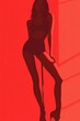© Espresso - A slim woman in a stylish pose, silhouetted against a vibrant red backdrop, exuding confidence and allure.