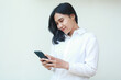 © M Alfan Setyawan - grateful pretty asian business woman satisfied using smartphone apps for online shopping wearing white formal suit shirt, browsing social media, read good news, standing over isolated background
