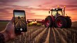 © Ashi - Smart farming technology: hand holding smartphone to control modern tractor in agricultural field for precision farming solutions and sustainable crop management