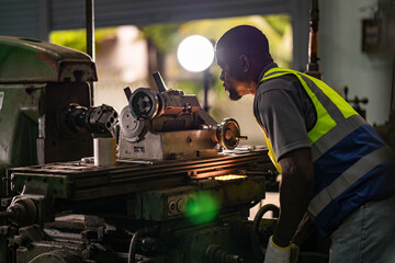 A focused technician operates heavy machinery in an industrial workshop. Dressed in a high-visibility vest, he exemplifies concentration and skill in a metalworking environment, ensuring precision.