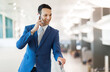© Minerva Studio - Smiling businessman talking on mobile phone at airport
