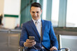 © Minerva Studio - Businessman texting on smartphone at airport