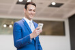 © Minerva Studio - Young professional man in a blue suit texts happily on his phone