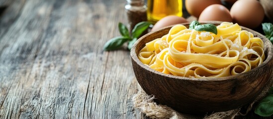 Poster - Pasta in a wooden bowl with vegetable oil and eggs placed on an aged wooden surface Italian cuisine Copyspace background