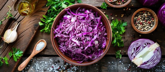 Leinwandbilder - Top view of fermented shredded cabbage in a bowl surrounded by cooking ingredients on a rustic wooden background in a horizontal layout with copyspace