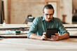 © peopleimages.com - Workshop, carpenter and man with tablet for reading, research and information for wood tips. Small business, male person and builder with digital for inventory management, check and track materials