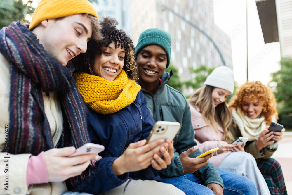 Diverse group of young friends using mobile phones sitting on a city ...