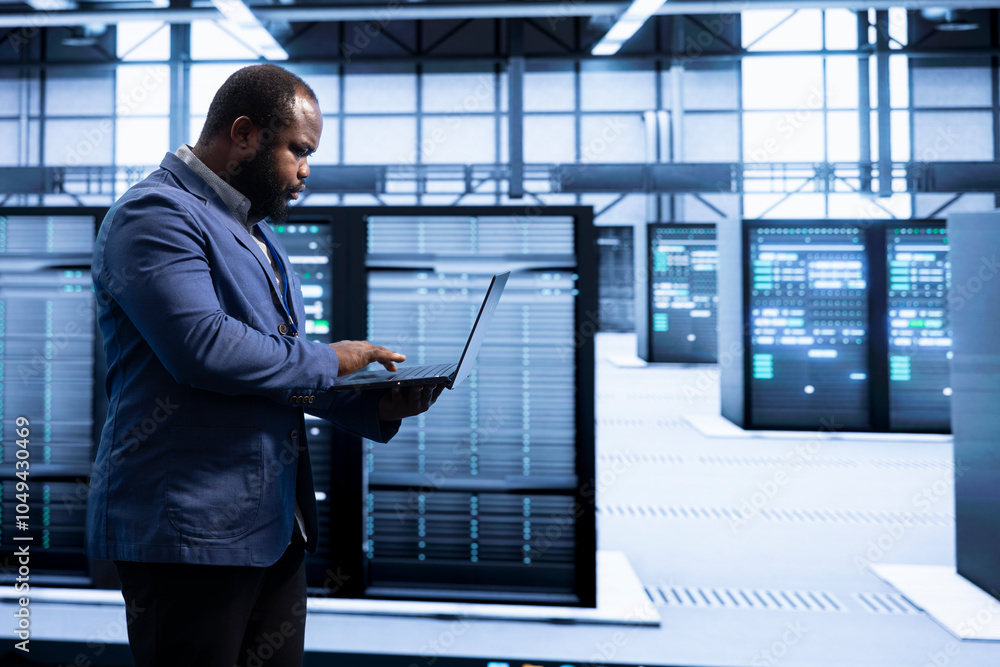 Computer scientist walking in data center, using laptop to configure ...