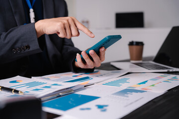 Wall Mural - businessman sits at his office desk, analyzing financial documents and graphs on his laptop. paperwork, calculator, and charts, he strategizes investments, audits, tax planning for success.