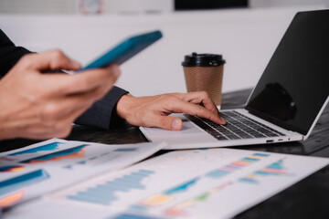 Wall Mural - businessman sits at his office desk, analyzing financial documents and graphs on his laptop. paperwork, calculator, and charts, he strategizes investments, audits, tax planning for success.