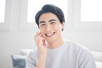 Beauty image of a young man with his hand on his cheek taking care of his skin, close-up looking at the camera, beard removal, etc.