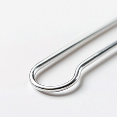 Wall Mural - close up of a shiny silver paperclip on a white background