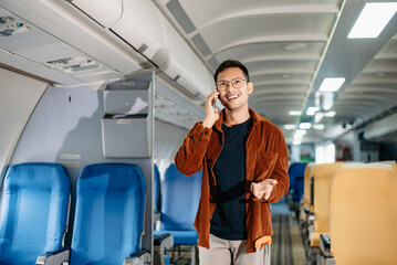 Asian male passenger of airplane sitting in comfortable seat while working laptop and tablet with mock up area using wireless connection. Travel in style,