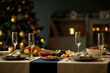 © Seventyfour - Still life shot of empty champagne flutes served with fruit and cheese platters on festive dinner table while Christmas lights glowing in blurred background, copy space