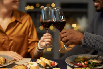 Wall Mural - Cropped shot of multiethnic couple enjoying red wine clinking glasses during romantic date at home dinner, copy space