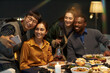 © Seventyfour - Candid shot of Asian man taking selfie with four cheerful friends while sitting at festive dining table celebrating Christmas at home party, copy space