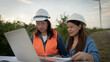 © Thanadon88 - Two Female engineer  are looking at a laptop together. One of them is wearing an orange vest. They are working on a project together