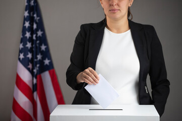 Voting women near ballot box on table against flag of USA