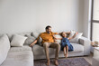 © fizkes - Joyful excited Latin dad and playful little daughter kid resting on spacious comfortable white home couch with open hands, laughing, having fun, enjoying carefree family leisure